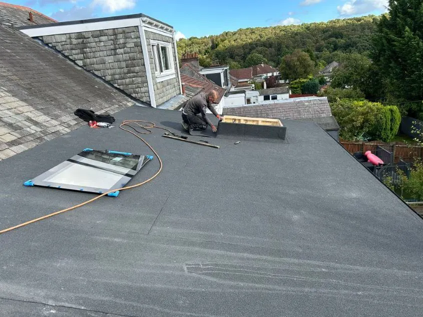 A flat roof being covered behind a house