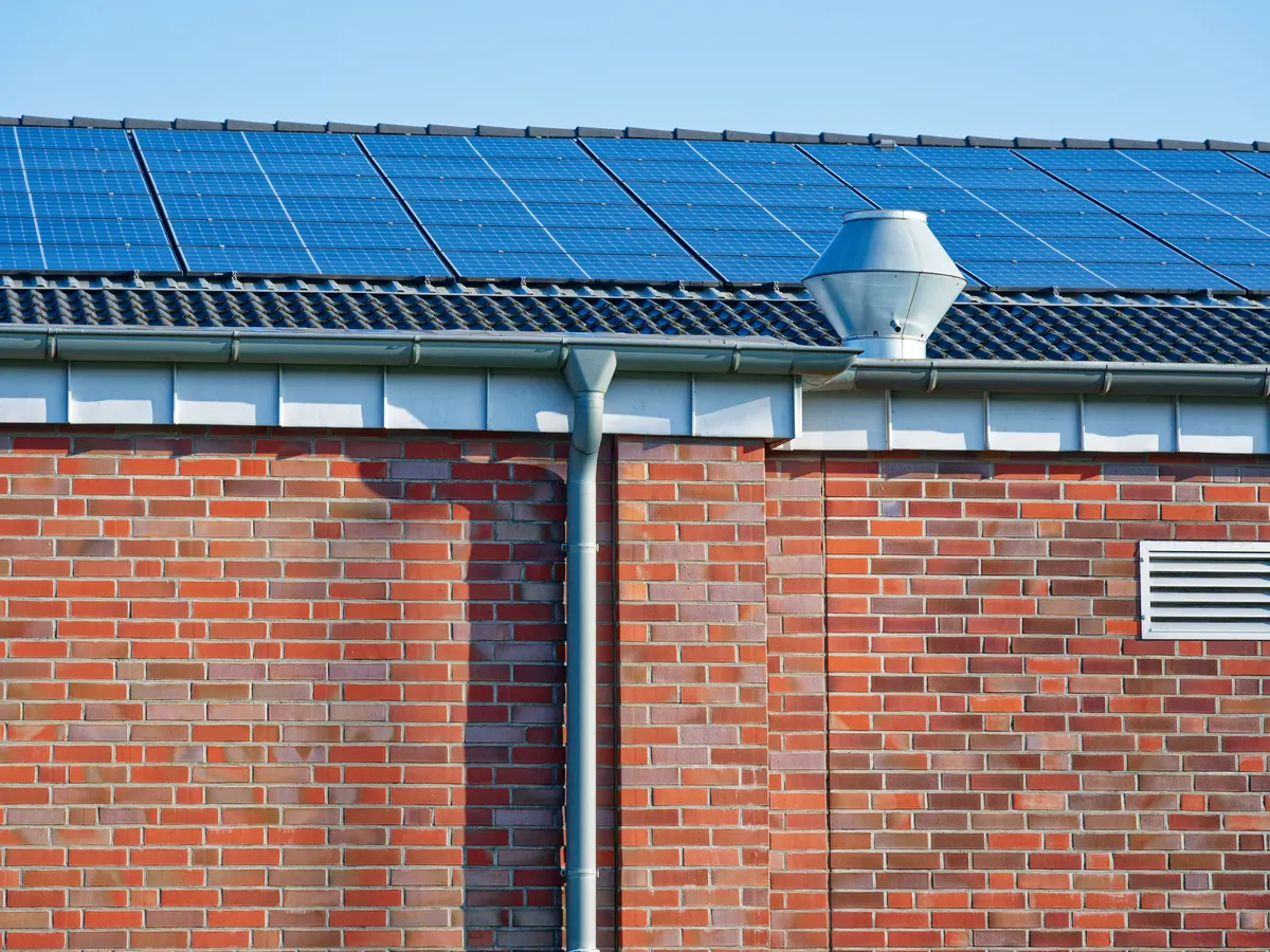 A commercial building roof with solar panels and metal guttering