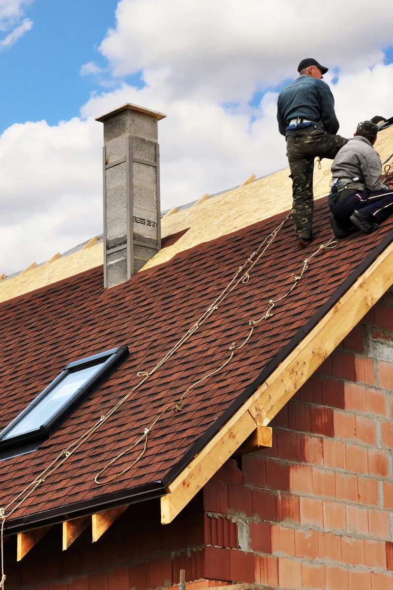 Two roofers fitting a new tiled roof with a roof window