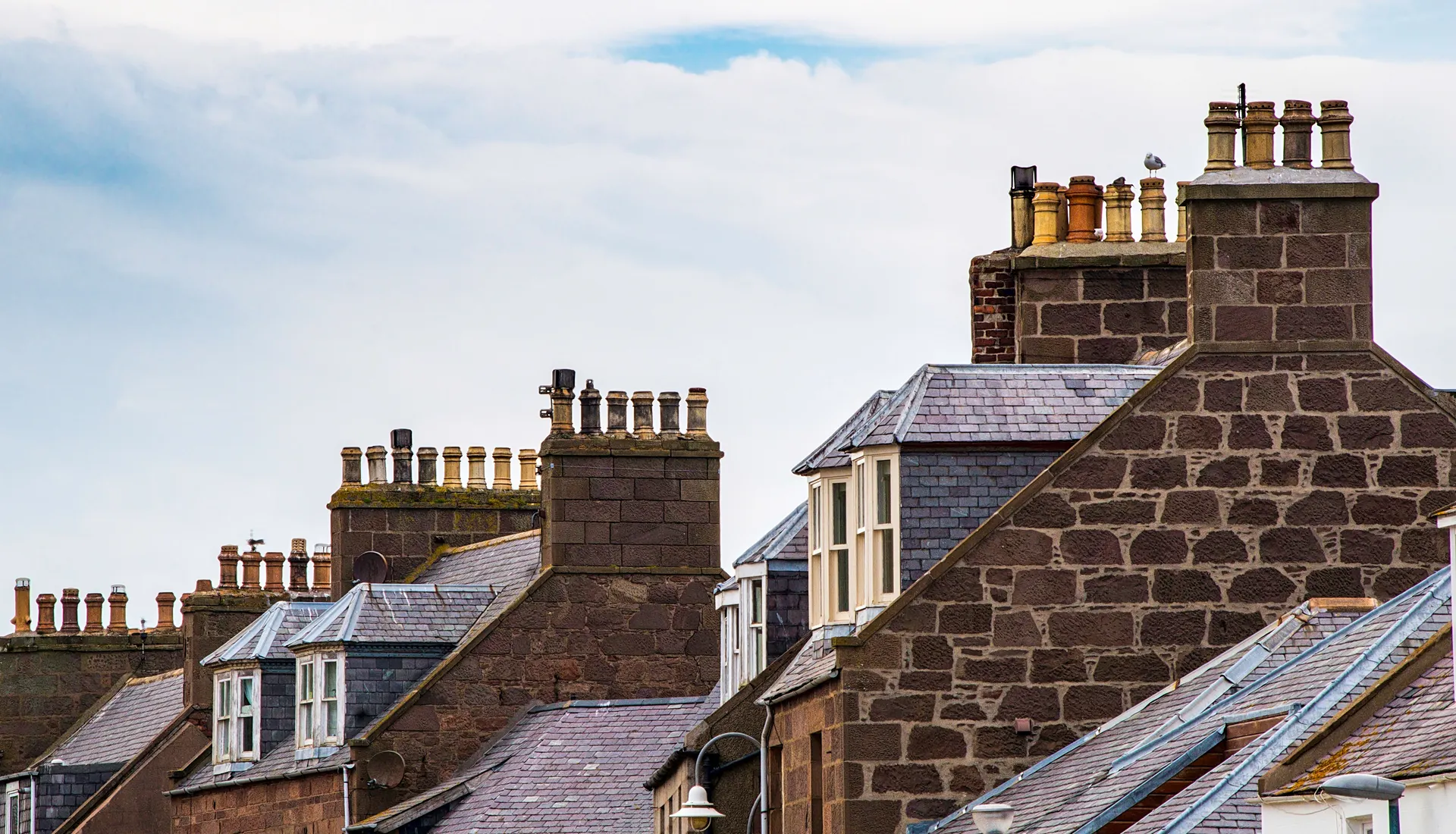 Slate roofs and chimney stacks on a row of Scottish stone houses