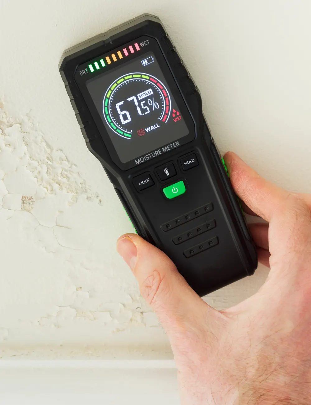 A moisture meter being used on a damp wall