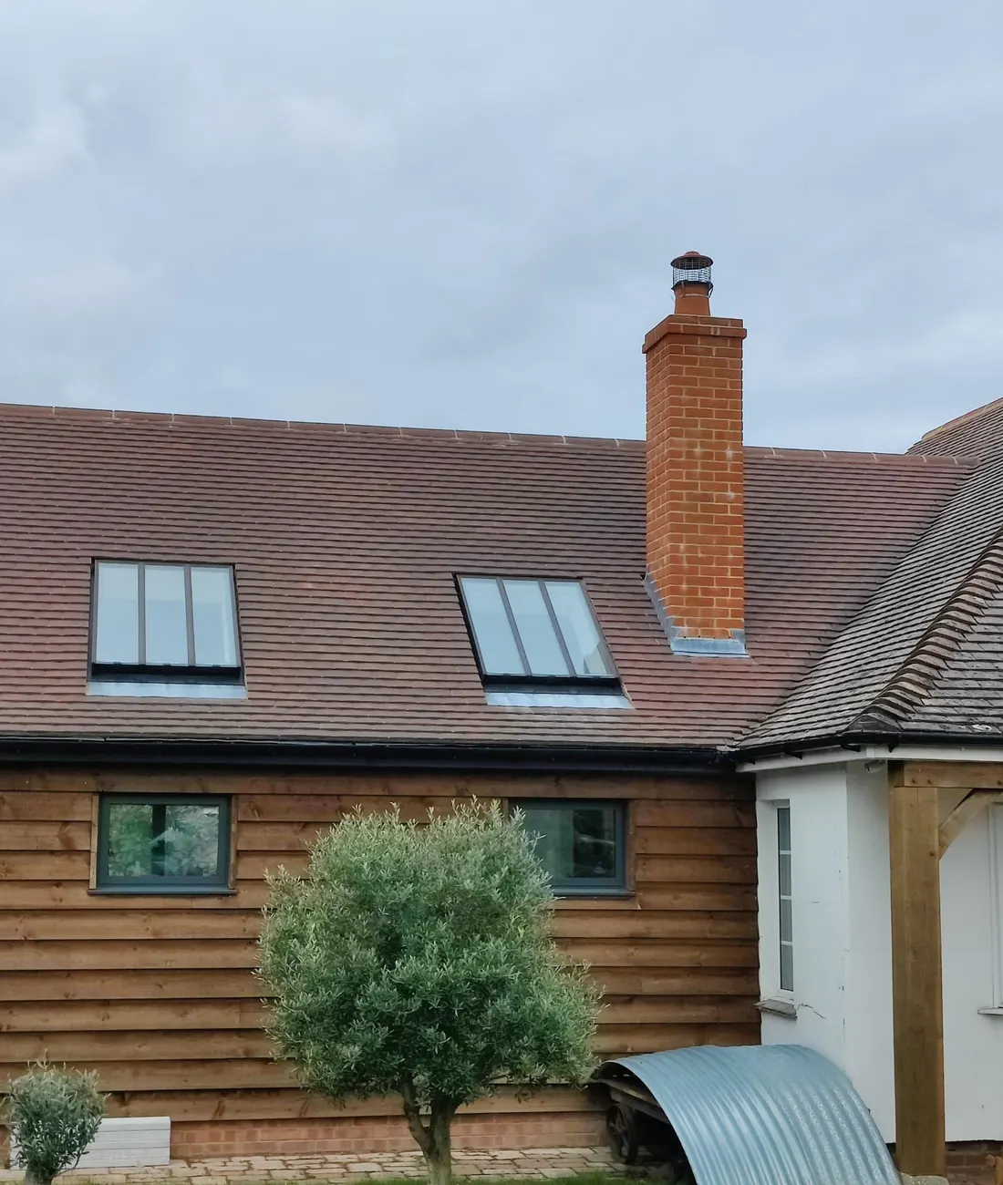 Red ridge tiles fixed along a grey tiled roof