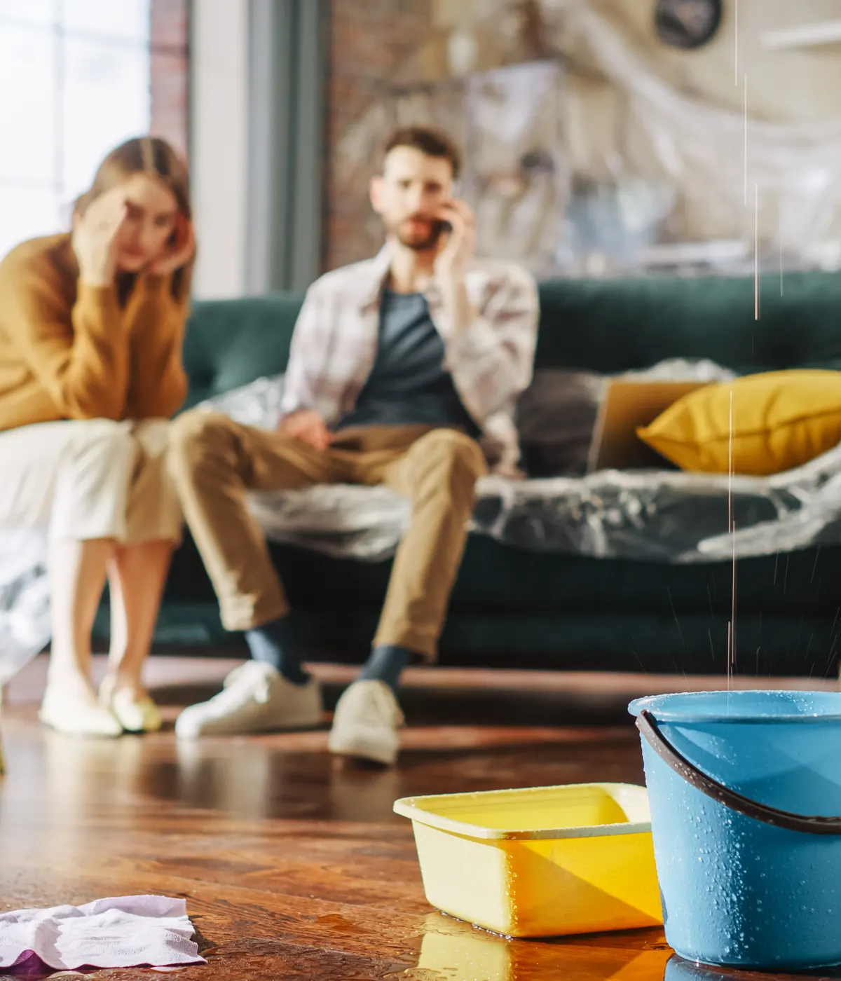 A couple inside their home with buckets catching a roof leak