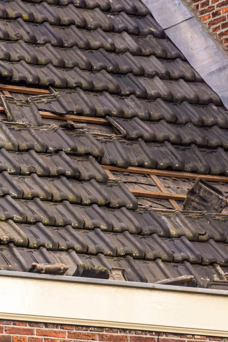 Missing and broken tiles on a storm-damaged roof