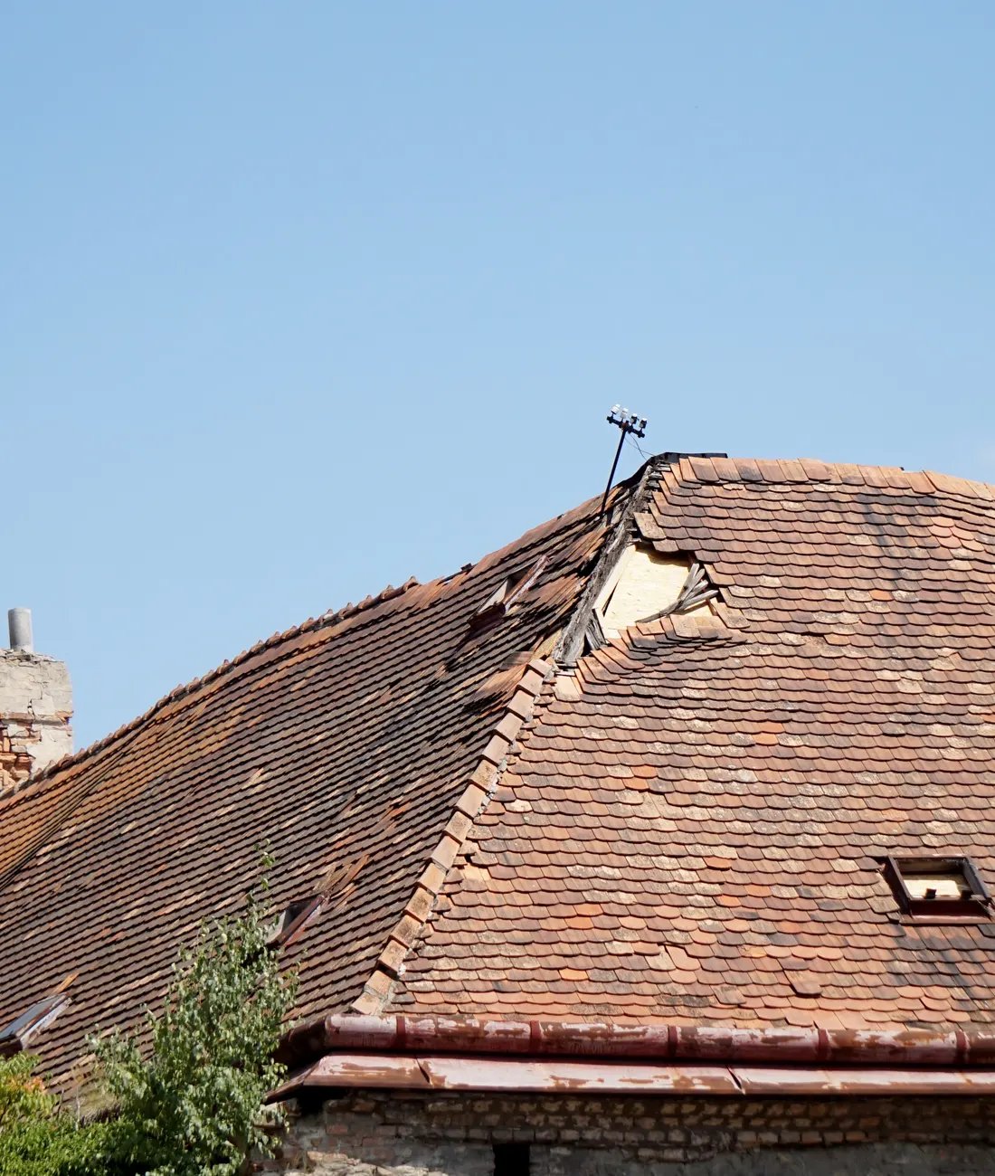 An old tiled roof with damage near the ridge