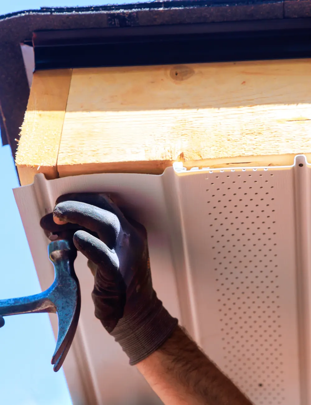 A fitter fixing a new soffit board under the eaves