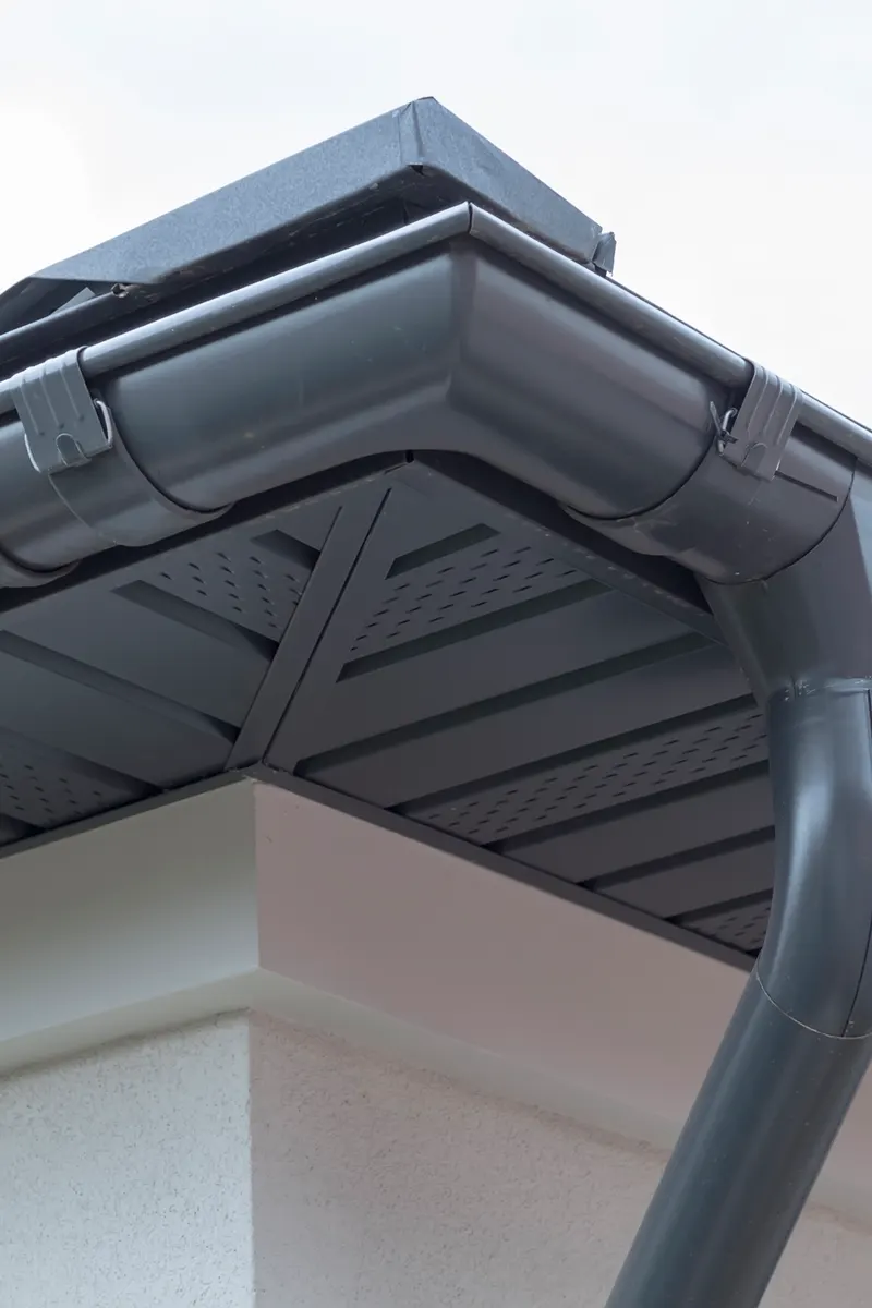 A corner of grey fascia and soffit with a downpipe