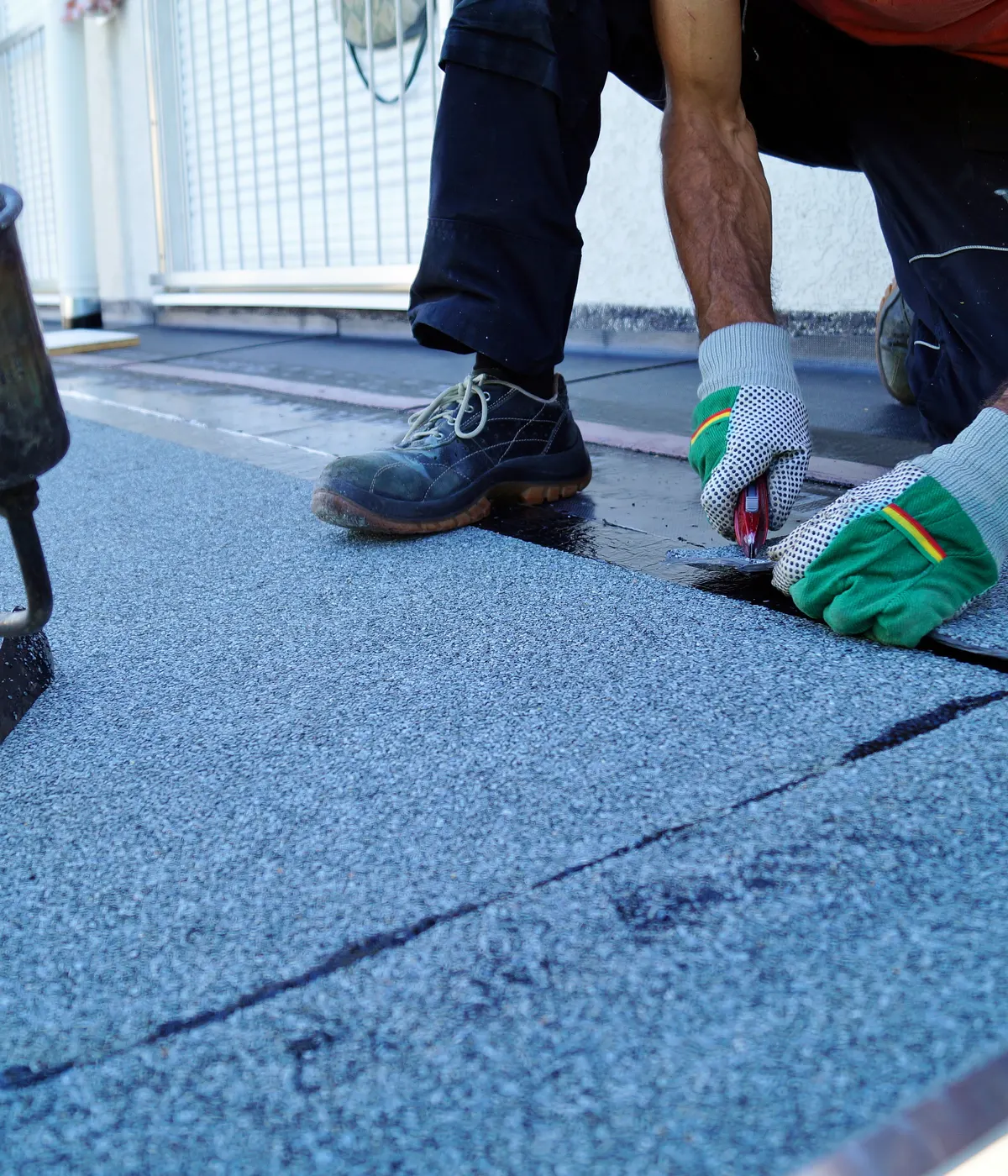 A roofer finishing the edge of a felt flat roof