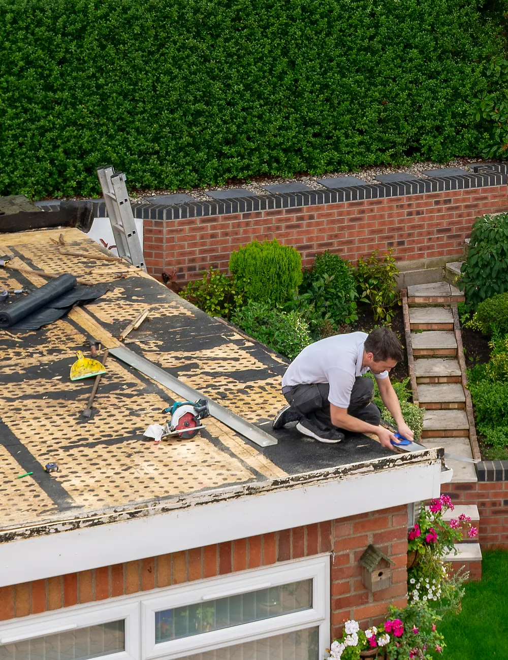 A roofer building a new flat roof on a house extension