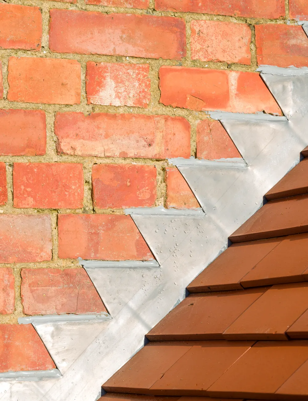 Stepped lead flashing where a tiled roof meets a brick wall