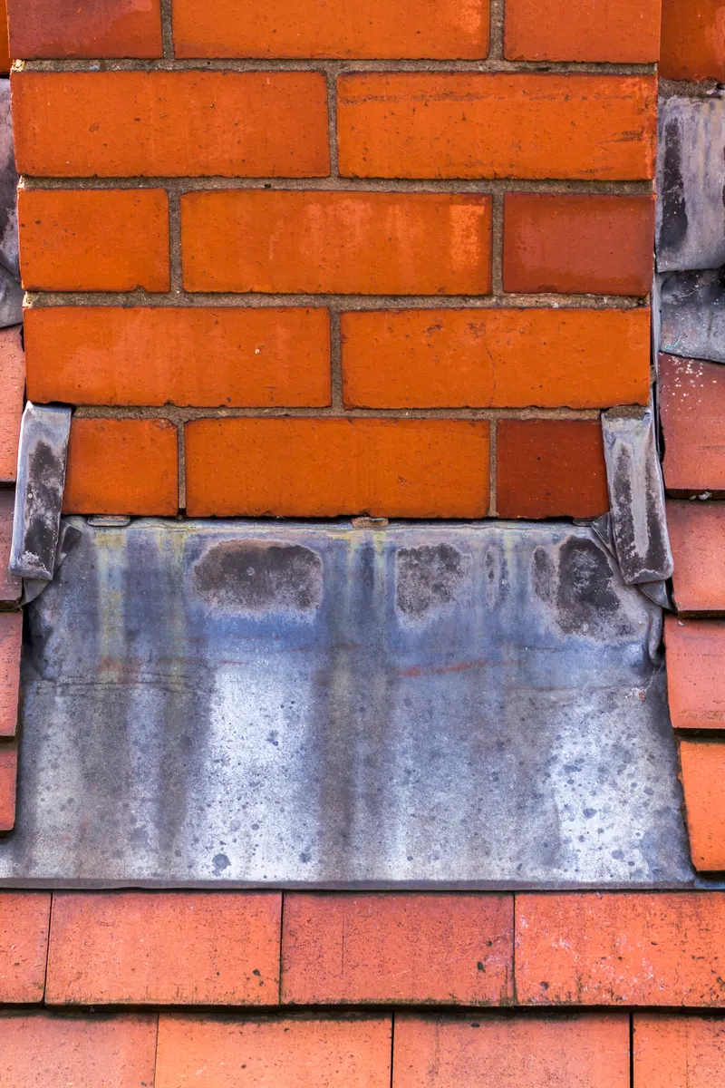 A lead apron flashing at the base of a chimney
