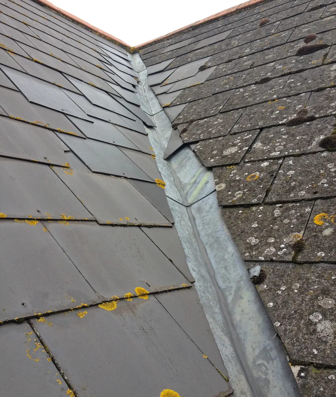 Lead flashing stepped up a brick wall beside a tiled roof