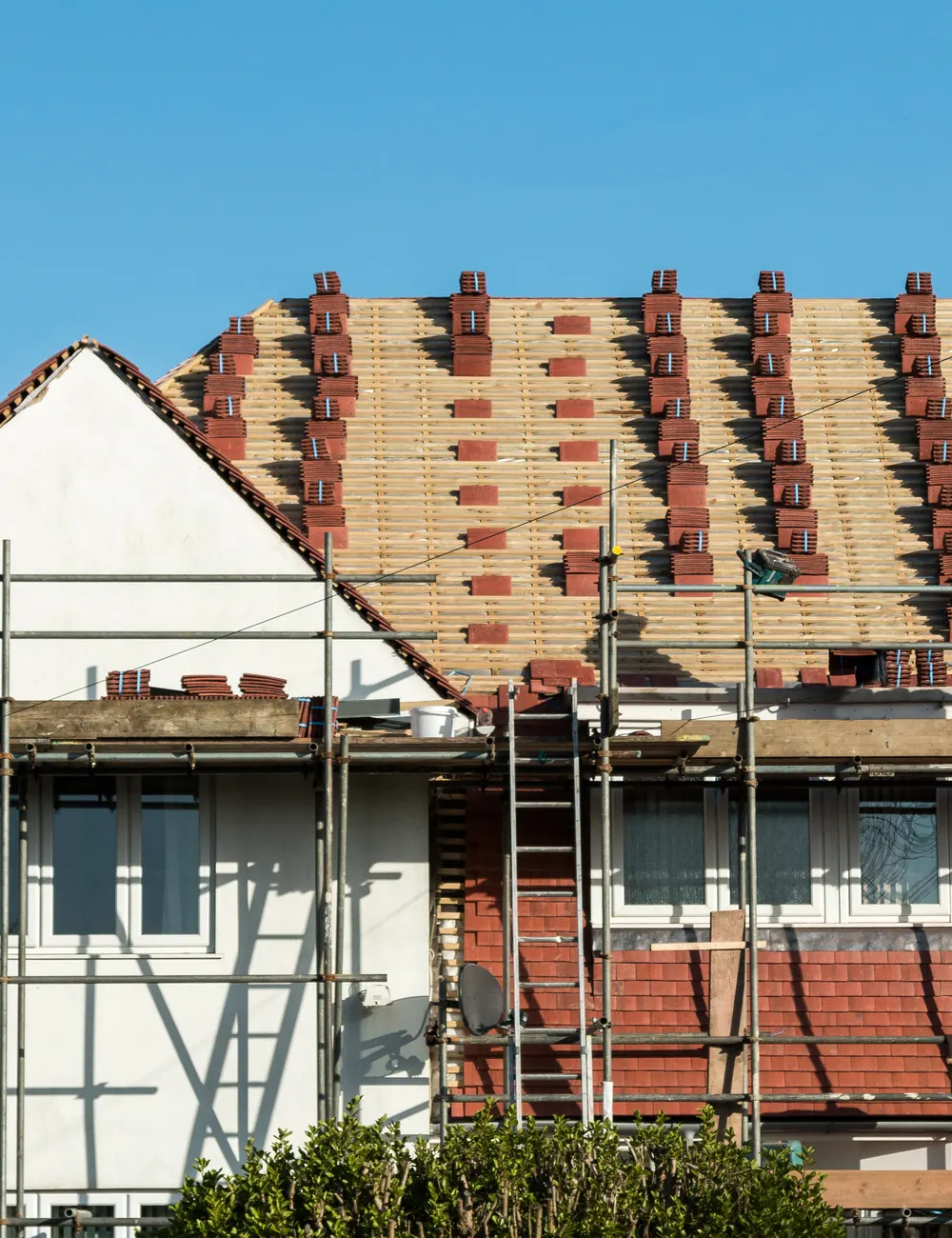 A house being re-roofed with new tiles stacked along the battens