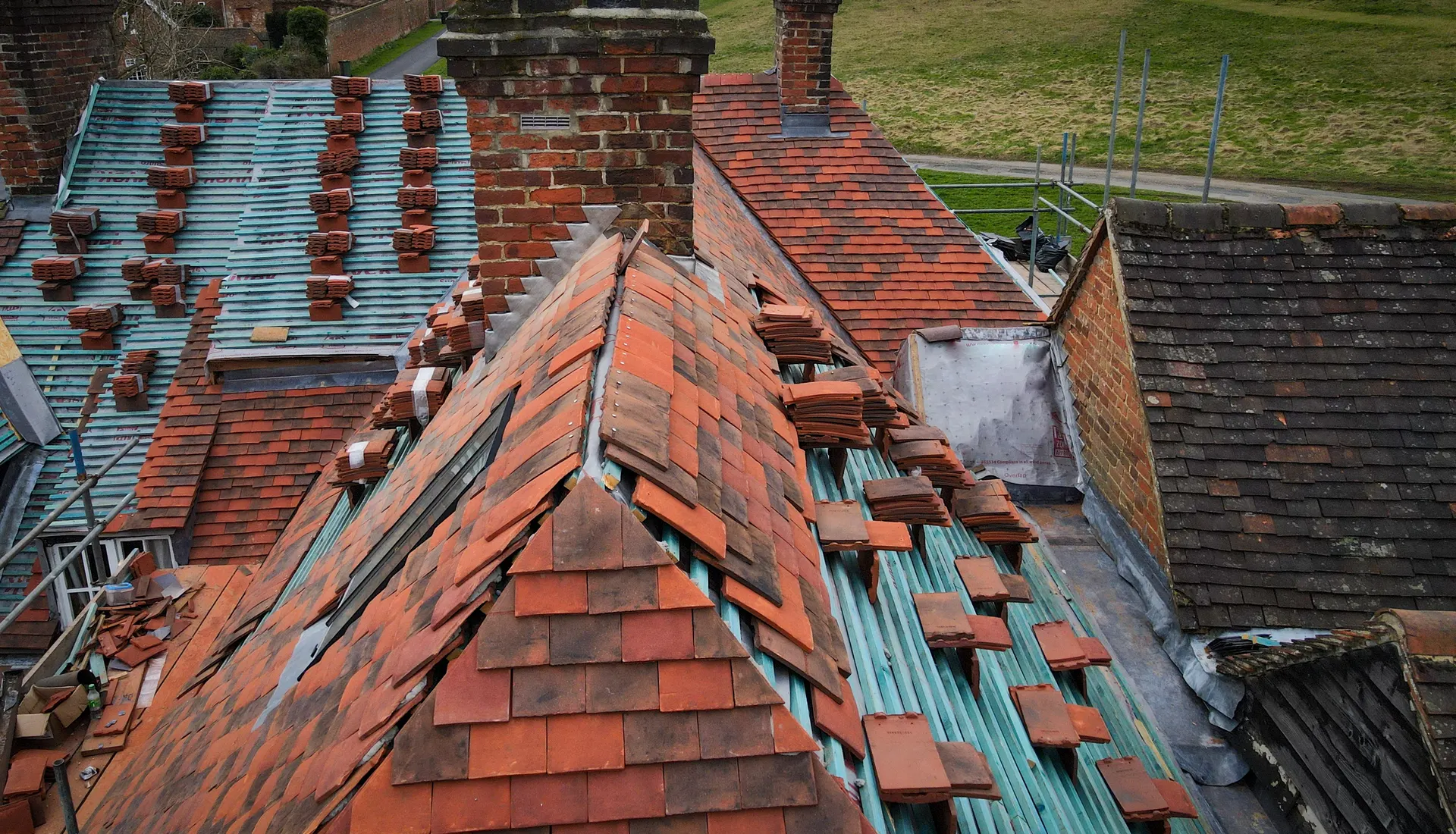 A clay tiled roof opened up for repair beside a chimney