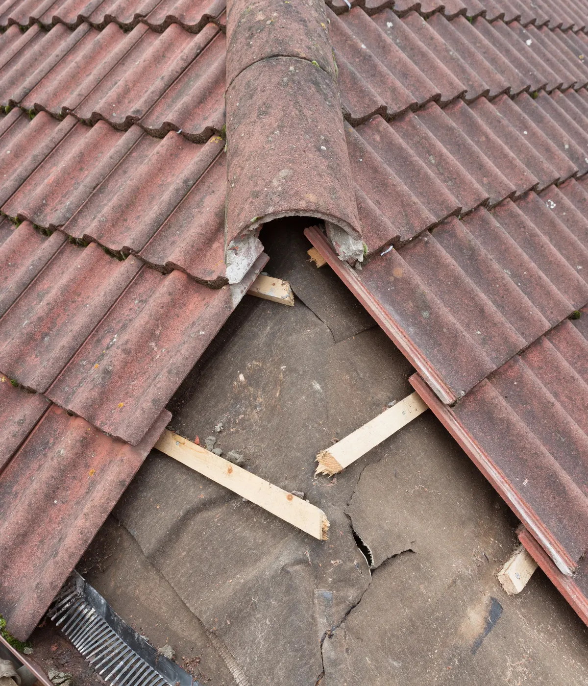 Broken roof tiles lifted to show the battens underneath