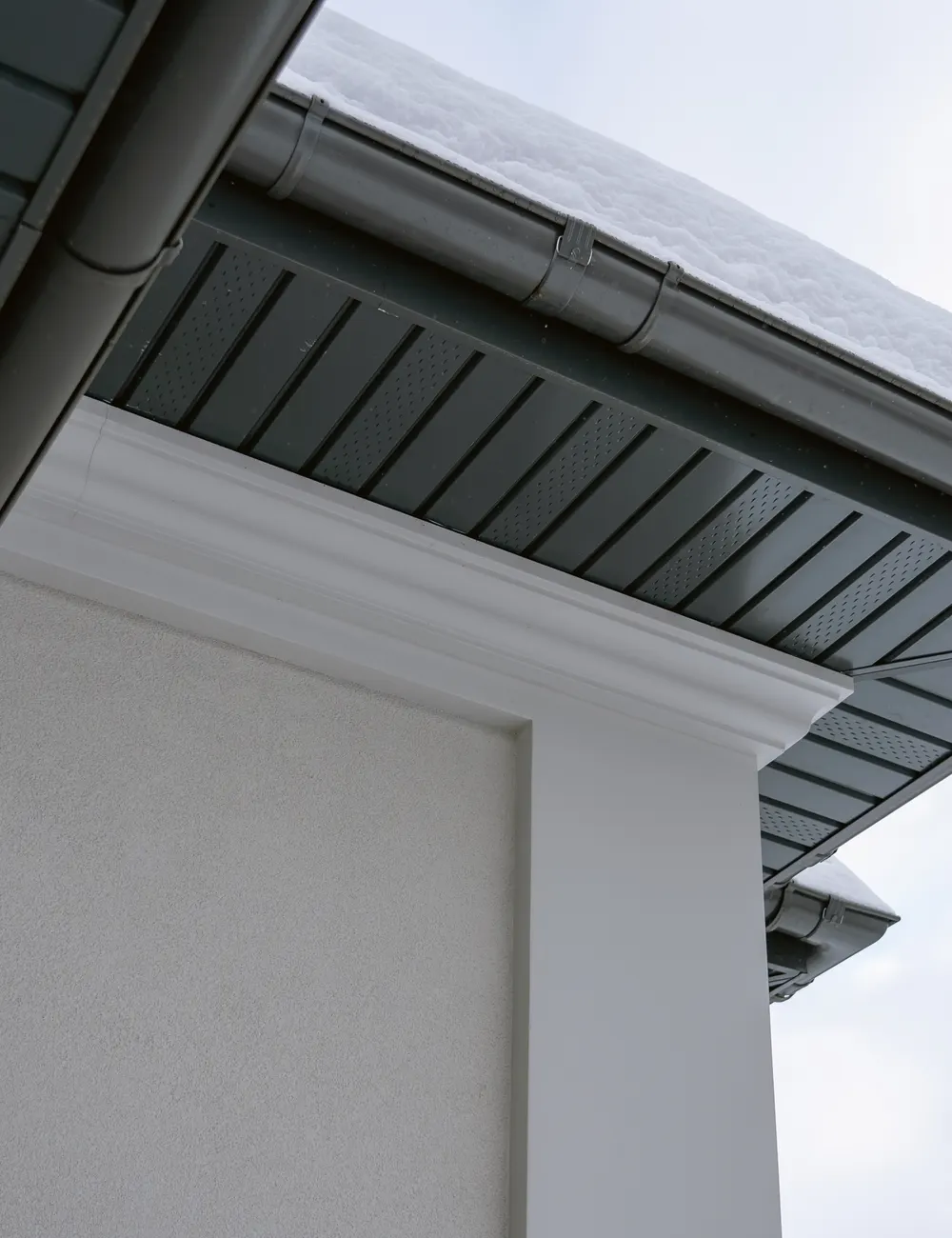 Grey soffit and fascia under the eaves of a white house