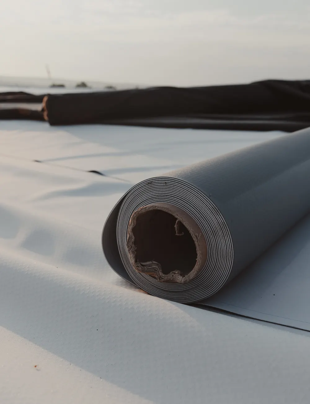 A roll of rubber roofing membrane on a flat roof