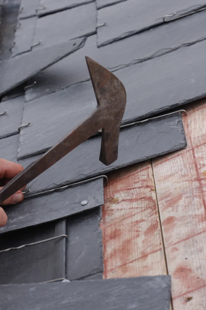A slater fixing a slate with a slater’s hammer